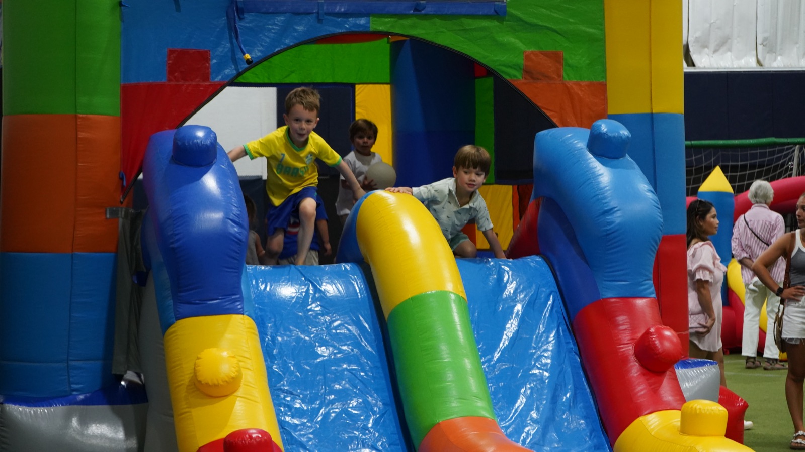 Kids climbing and sliding on colorful bounce houses at a Bedford Field House birthday party.