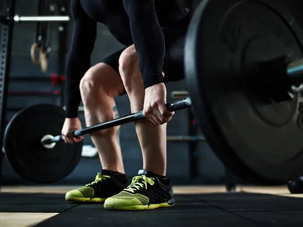 Athlete setting up a barbell deadlift in the strength training area.